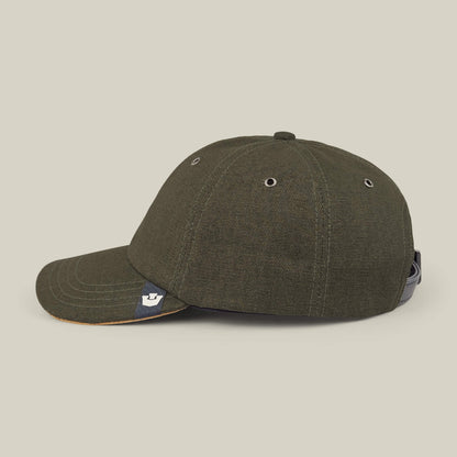 The Goorin Bros. Mineral Road cap features mixed materials in dark green, metal eyelets, a black back adjustment strap, and a small branded tag by the brim, displayed against a light background.