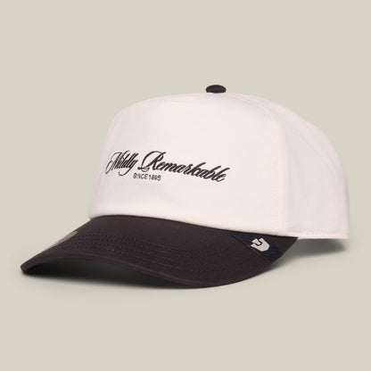 The Goorin Bros. Mildly Remarkable Script cap is a white low pro fit baseball hat with a black brim and classic bold black “Mildly Remarkable SINCE 1895” script embroidered on the front.