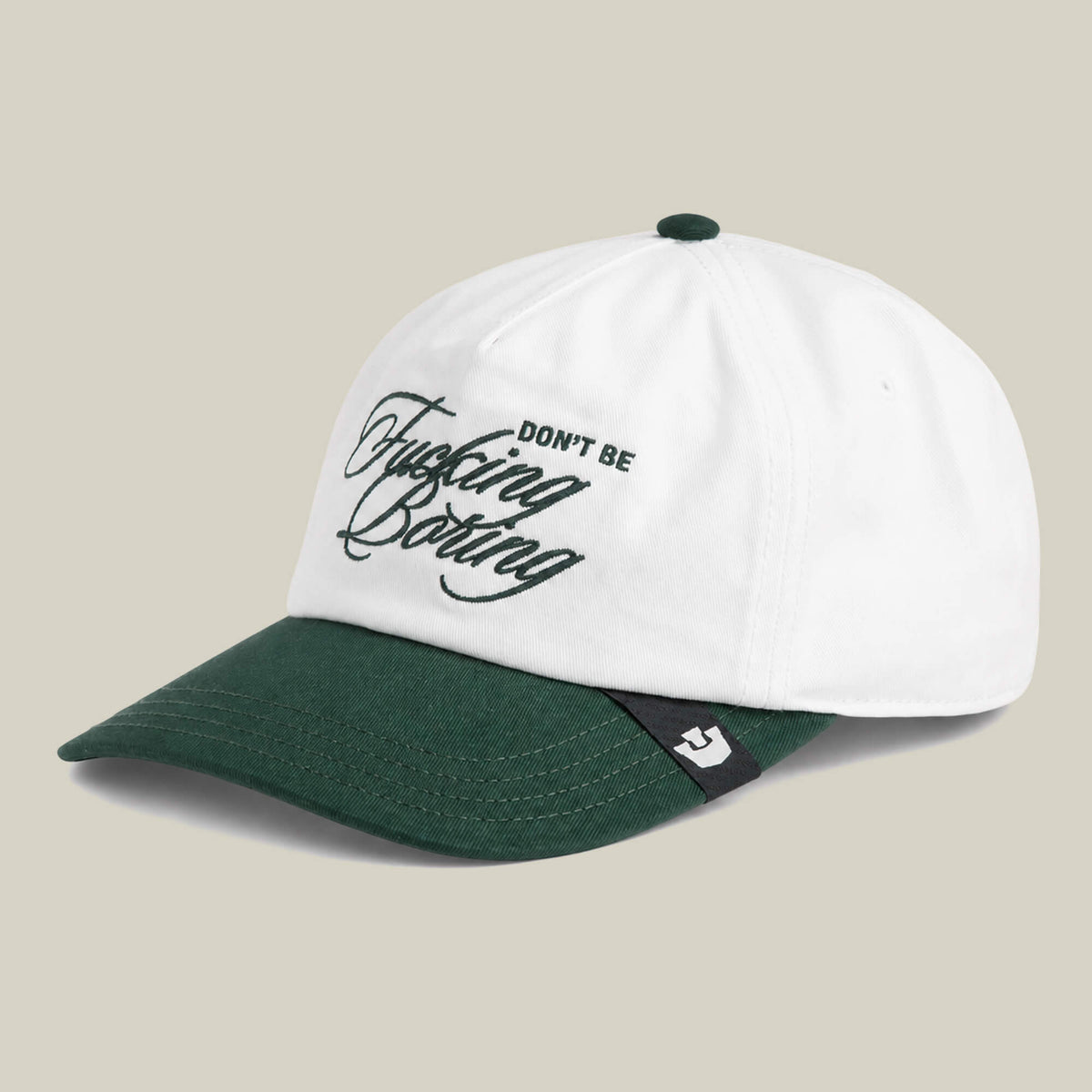The Goorin Bros. "Don't Be Fucking Boring" cap features a white and dark green two-tone design with the phrase embroidered in cursive on the front.