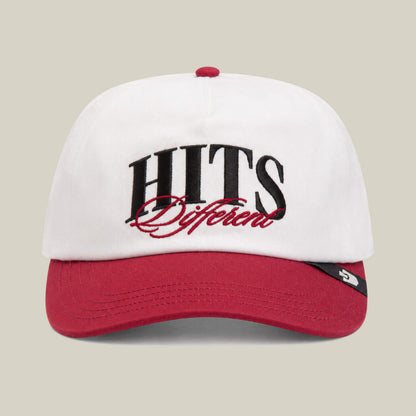The Goorin Bros. Hits Different cap in Dust/Crush features a red curved brim and bold front embroidery of "HITS Different.