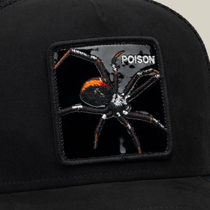 A black patch featuring an embroidered spider and the word "POISON" is sewn onto a black fabric surface, forming part of the Goorin Bros. Black Out Spider hat—an eye-catching collectible trucker piece that channels bold spider energy.