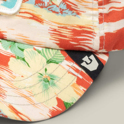 Close-up of two fabric hats with red and beige floral patterns; one is the Goorin Bros. Funemployed Forever papa cap featuring a black tag with a white geometric logo.