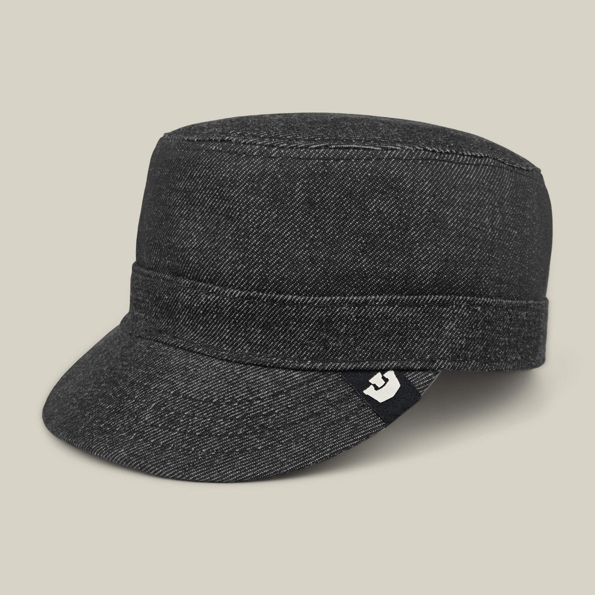 The Devonshire by Goorin Bros. is a dark gray hand-sewn cotton cadet cap with a short flat brim and a small black tag with a white graphic near the band, made in the USA and shown on a plain beige background.