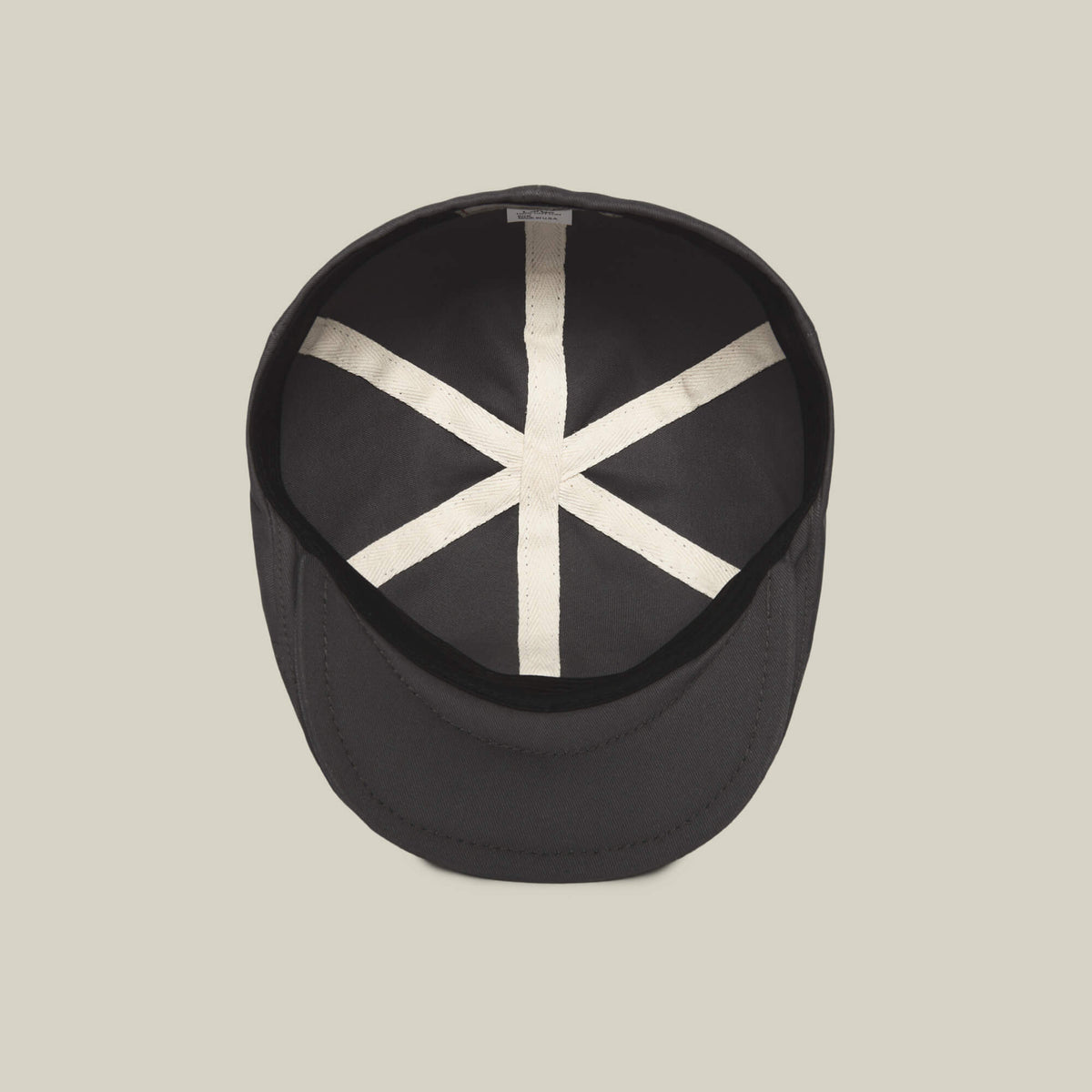The Goorin Bros. Murray Way is a black flatcap shown from above on a beige background, featuring a white X and vertical line inside the crown. Crafted from 100% cotton for comfort and style.