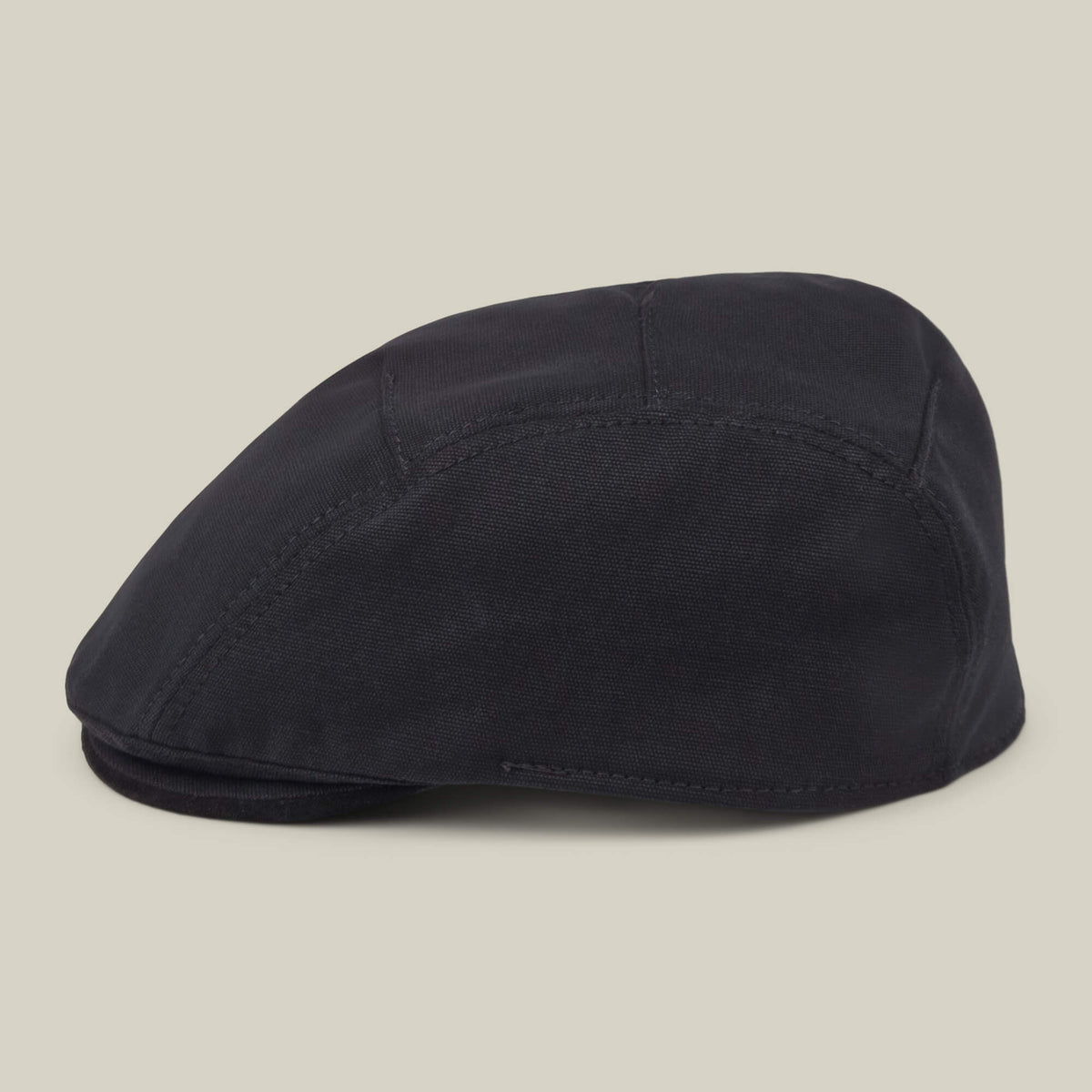 The Heatherwood flatcap by Goorin Bros., crafted from black cotton suede in the USA, is displayed side-on against a plain beige background.