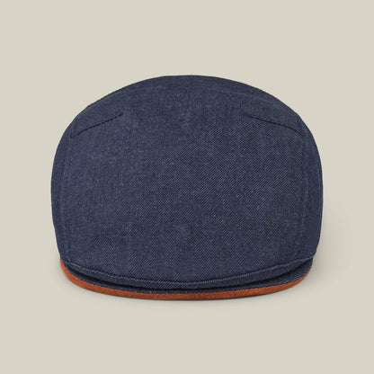 The Goorin Bros. Ashfield flat cap in dark denim cotton suede features visible stitching and a brown trim, made in the USA and shown against a plain beige background.