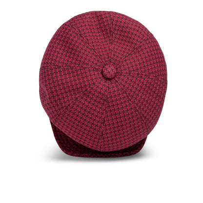 A maroon and black houndstooth Goorin Bros. Cold Snap cabbie flatcap is viewed from above, displaying the button on top and the partially visible brim at the bottom. Made in America, this cap features a comfortable German wicking sweatband for all-day wear.