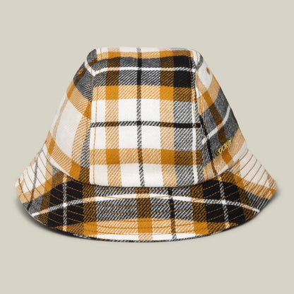 The Goorin Bros. Bespoke Wordmark Bucket hat in AMBER features a plaid pattern in yellow, black, and white, displayed against a plain beige background.
