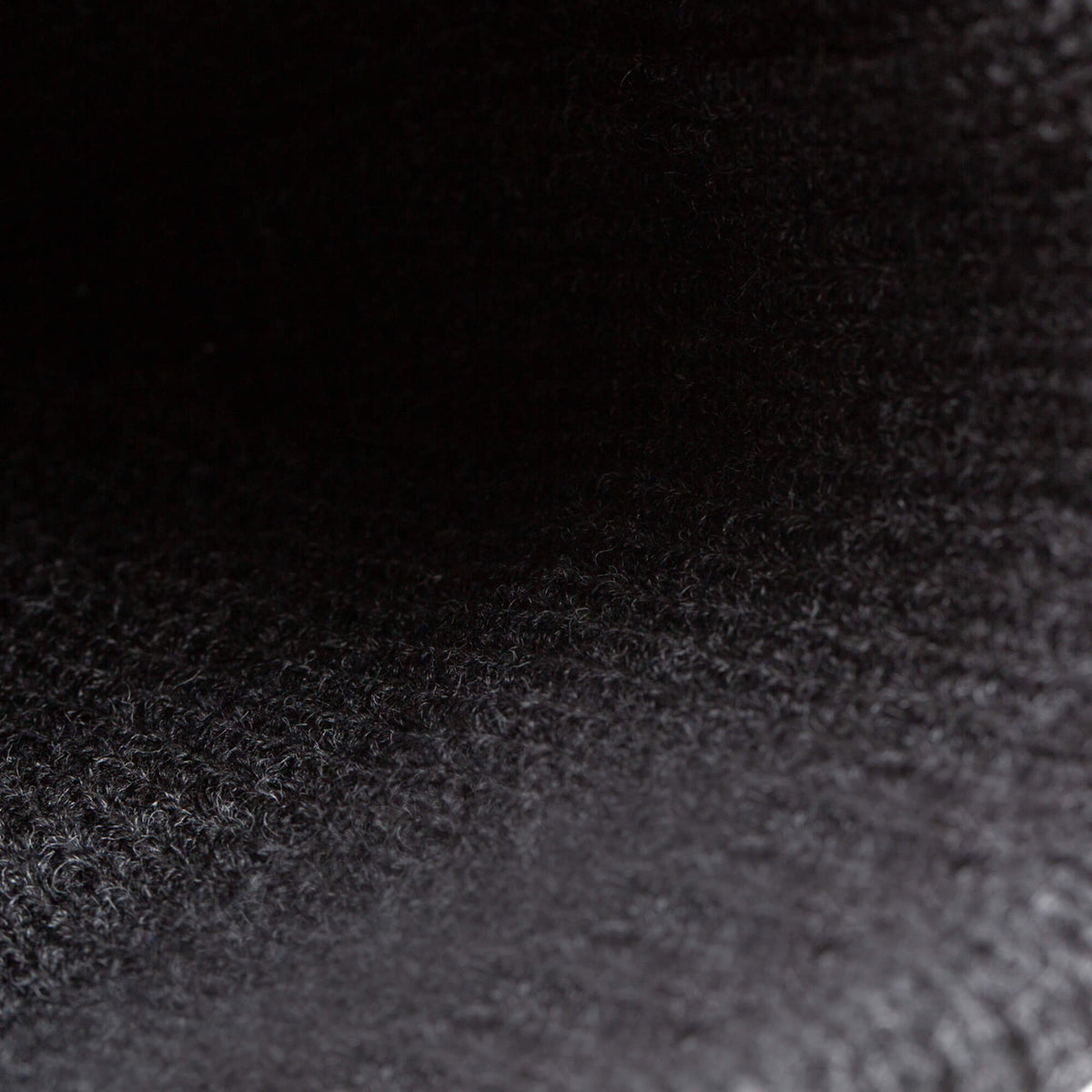 Close-up of The Beware Beanie by Goorin Bros., showing its dark, heavyweight knit material with a textured and slightly fibrous surface under low lighting.