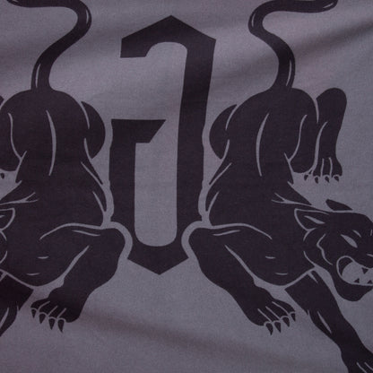 Two stylized panthers face away from each other with a bold, abstract “J” between them on a gray background—perfectly featured on the Goorin Bros. Panther Crest Blanket to add striking style to any throw blanket collection.