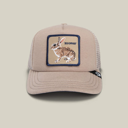 The OK Zoomer by Goorin Bros. is a beige mesh trucker hat featuring an embroidered rabbit patch and the word "ZOOMER" on the front—an ideal playful cap for kids.