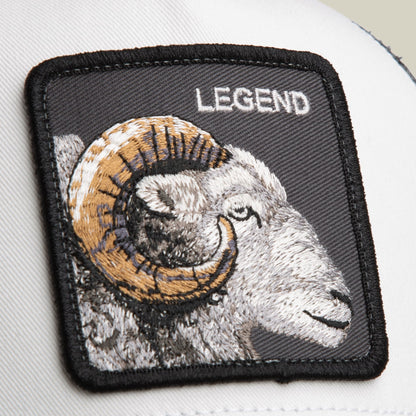 The Goorin Bros. Legend Trucker Mini features an embroidered ram head patch with gold horns and white fur on a black background, displayed as a close-up product shot.