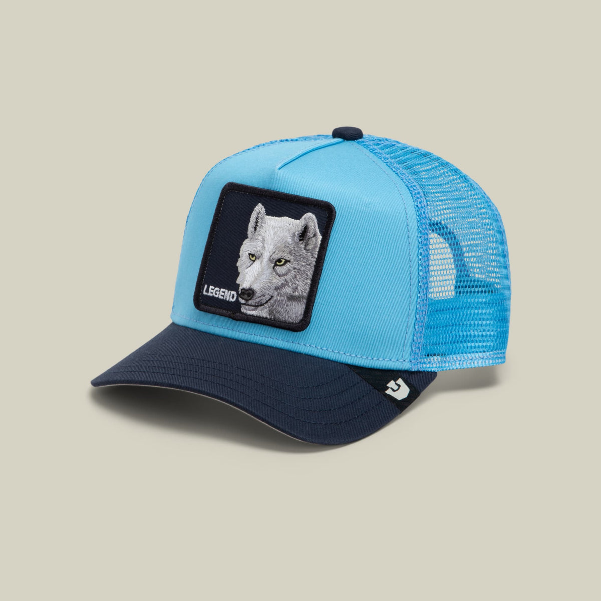 The Goorin Bros. Legend Wolf Trucker Mini is a light blue and navy mesh snapback cap featuring an embroidered wolf patch with "Legend" text on the front panel, shown on a neutral beige background.