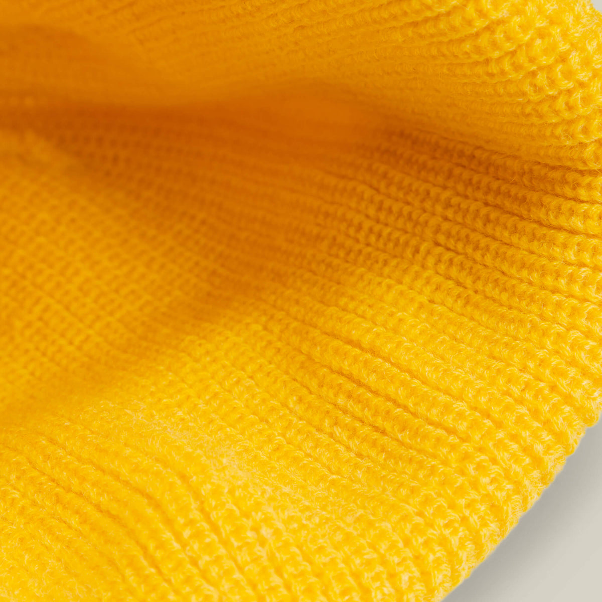 Close-up view of The Curious Beanie Mini by Goorin Bros.: a bright yellow knit with ribbed texture and fine stitching, ideal for playful kids’ beanies or adding a cute cat patch.