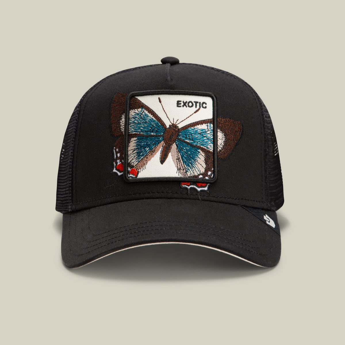 Introducing the Over the Line Butterfly cap by Goorin Bros.—a black mesh baseball cap crafted from a comfortable polyester-cotton blend. Featuring a front patch with an embroidered blue butterfly and the word “EXOTIC,” this breathable hat is the perfect way to add a touch of flair to your casual style.