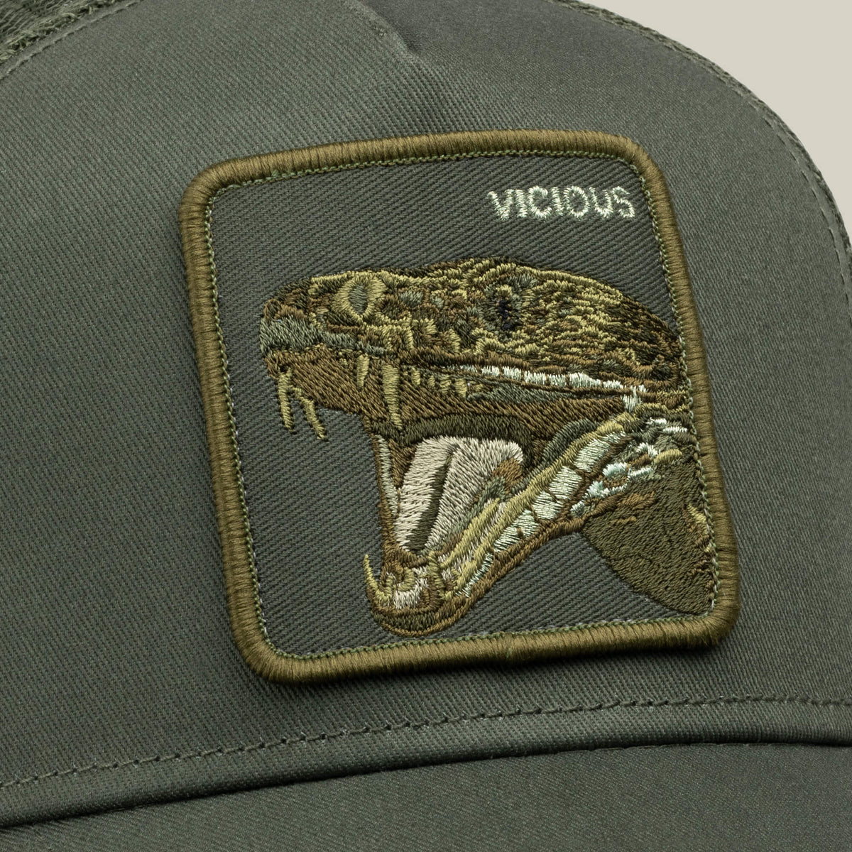 Close-up of the Goorin Bros. “Circle of Life - Vicious” olive-green trucker hat with an adjustable snapback and mesh back, featuring a patch with an embroidered snake head, mouth open, and the word “VICIOUS” stitched above.