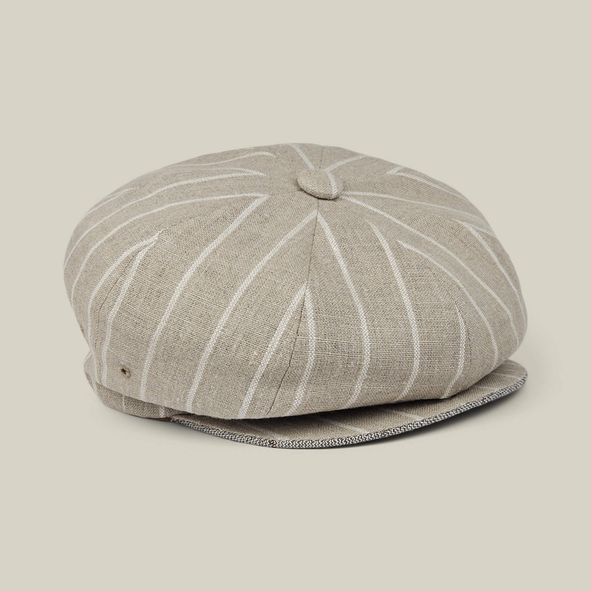 Rincon Park by Goorin Bros. is a beige linen blend newsboy cap featuring white vertical pinstripes and a button detail on top, hand cut and sewn for a classic Gatsby silhouette, displayed on a neutral background.