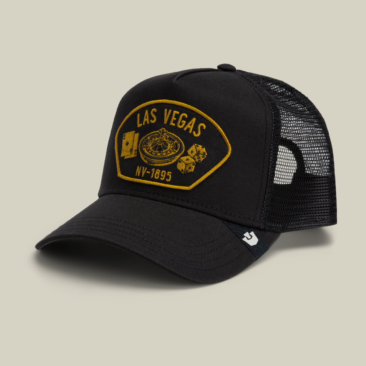 The Goorin Bros. Las Vegas trucker hat features a black mesh back for breathability and comfort, along with an embroidered patch that reads “Las Vegas NV-1895” and showcases images of playing cards, a roulette wheel, and dice.
