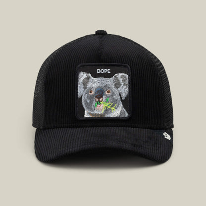 The Goorin Bros. Corduroy Dope is a black corduroy trucker hat with a mesh back and features an embroidered patch of a koala eating leaves, with the word “DOPE” above the image.