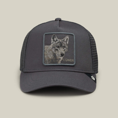 The Goorin Bros. Circle of Life – Loner is a gray mesh trucker cap, featuring an embroidered wolf patch with the word “LONER” beneath the wolf’s face on the front panel. Displayed against a light beige background, this stylish snapback hat stands out for its unique design.