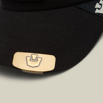 Close-up of the Castle CapLoc by Goorin Bros.—a black cap featuring a gold rectangular zinc alloy brim clip, adorned with an abstract logo for a stylish hat accessory.