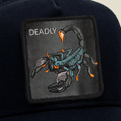 A black patch on this Goorin Bros. Deadly Scorpion trucker hat showcases an embroidered scorpion insignia with bold orange accents and the word “DEADLY” in white text at the top left. The mesh back ensures comfort and breathability for a striking finishing touch.