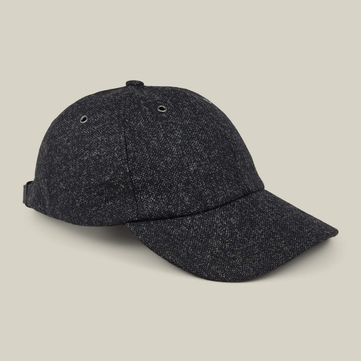 The Valmont baseball cap by Goorin Bros. is crafted from dark gray wool and features a curved brim, side adjustment strap, and two ventilation eyelets on each side. Made in the USA, it is displayed against a light beige background.
