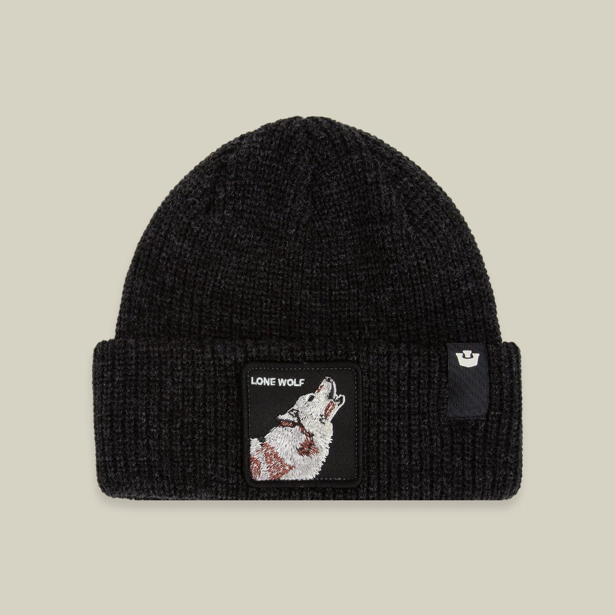 The Lone Wolf Beanie by Goorin Bros. is a black knit hat featuring a howling wolf patch with the words “LONE WOLF” on the front, along with a small logo tag on the cuff. Displayed against a beige background, this winter hat combines warmth and style.