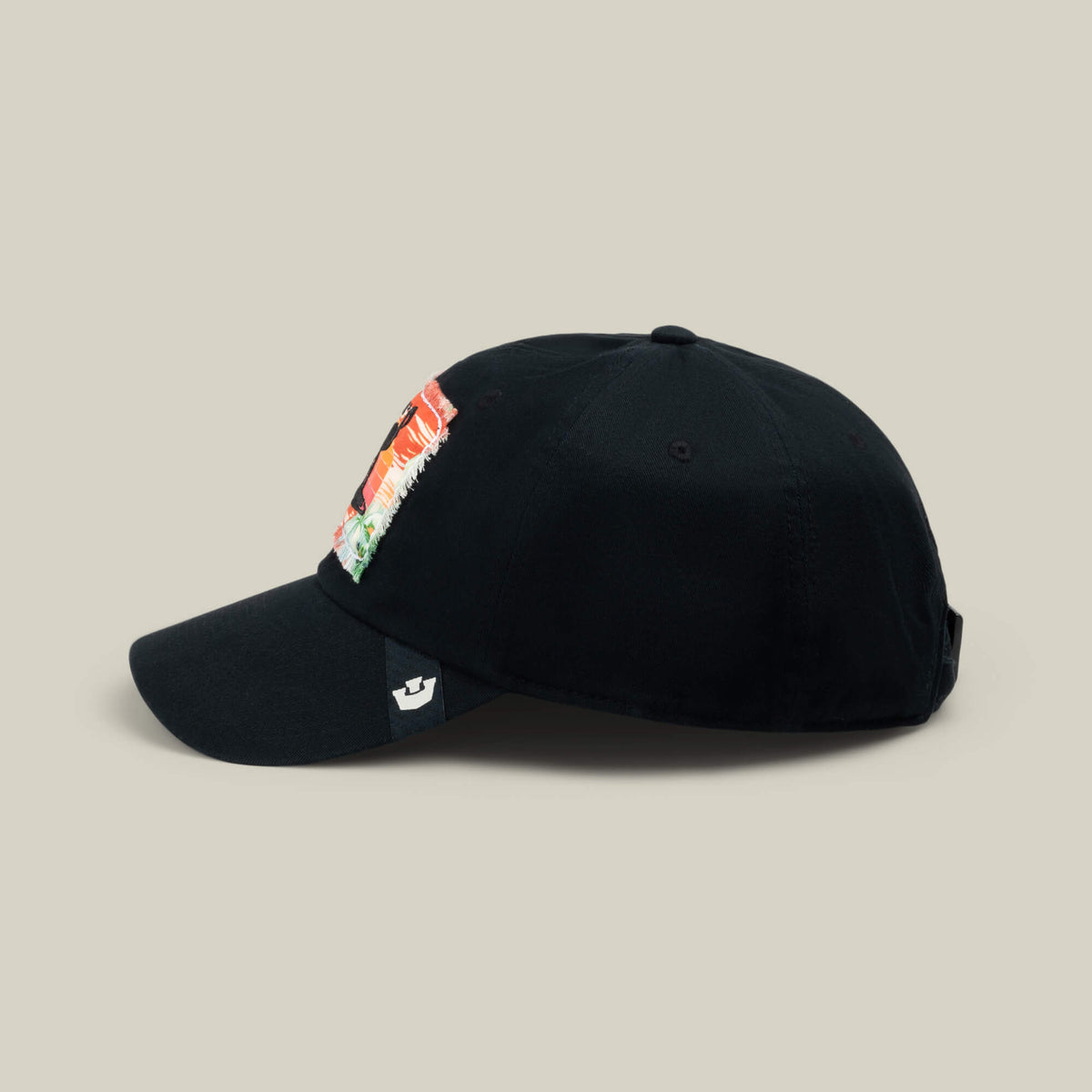 Black baseball cap with a curved brim and a colorful rectangular patch on the side, displayed on a plain beige background—a subtle nod to Goorin Bros.’ PTO, where comfort meets style as seamlessly as relaxation meets your next getaway.