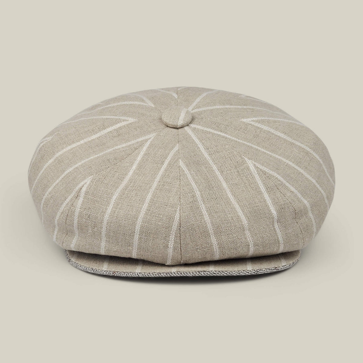 The Rincon Park by Goorin Bros. is a beige linen blend newsboy cap with white pinstripes, featuring a classic Gatsby silhouette with a button on top and a short, curved brim. Each cap is hand cut and sewn, and it is displayed against a neutral background.