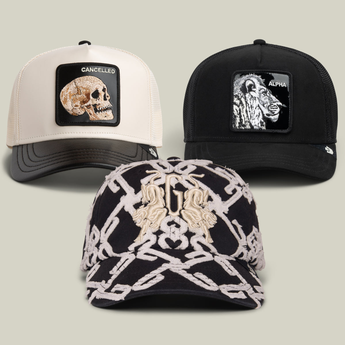 Three caps from Goorin Bros.’ “Black and White and Rad All Over” collection: one white cap with a skull patch labeled CANCELLED, one black cap with a lion patch labeled ALPHA, and one black patterned cap featuring embroidered animal designs on the front—all meticulously crafted from premium materials for bold visual impact.