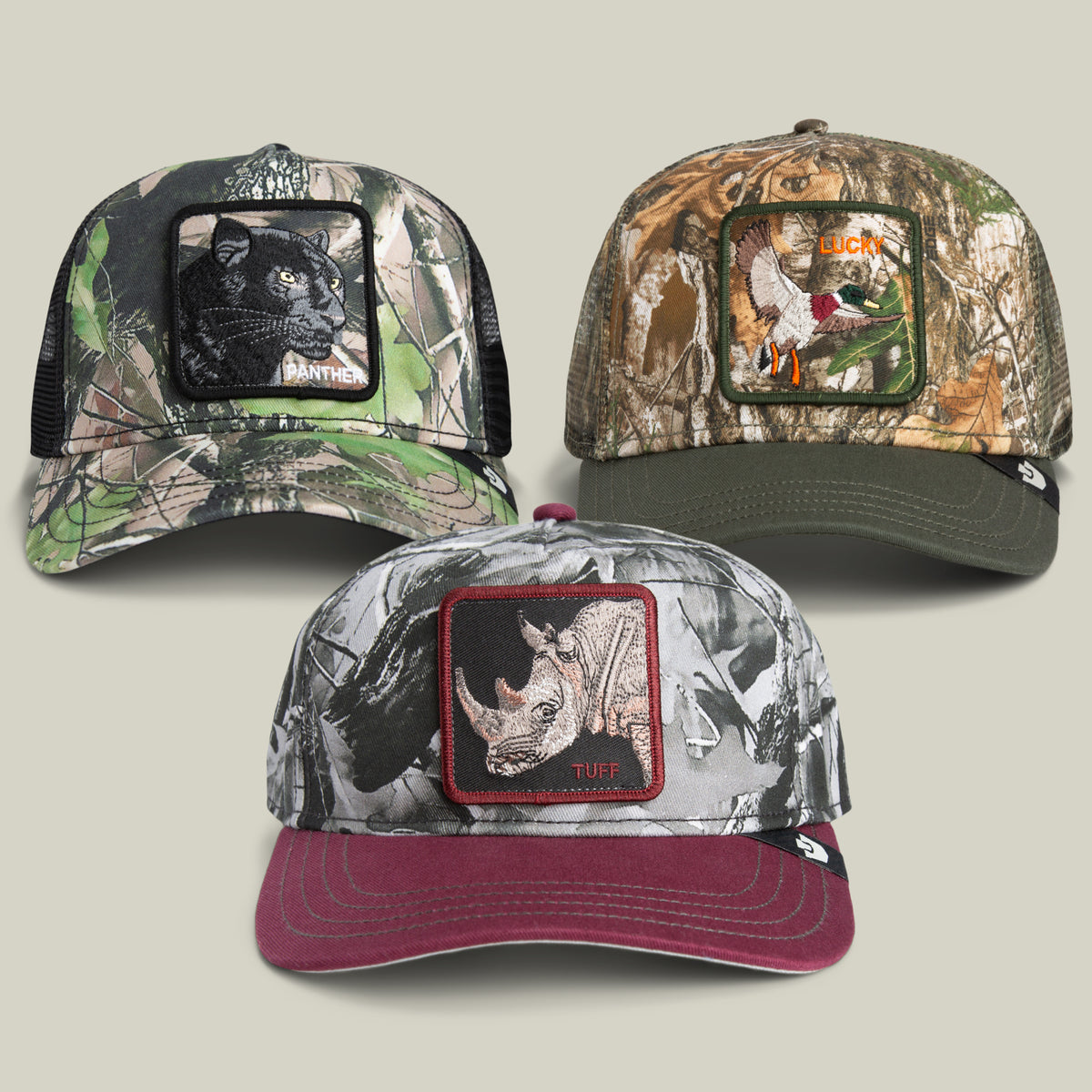 Three baseball caps from the Goorin Bros. Now You See Me Bundle, each showcasing a different camouflage pattern and a distinctive animal patch—panther, duck labeled LUCK, and rhinoceros labeled TUFF—are displayed against a light background.