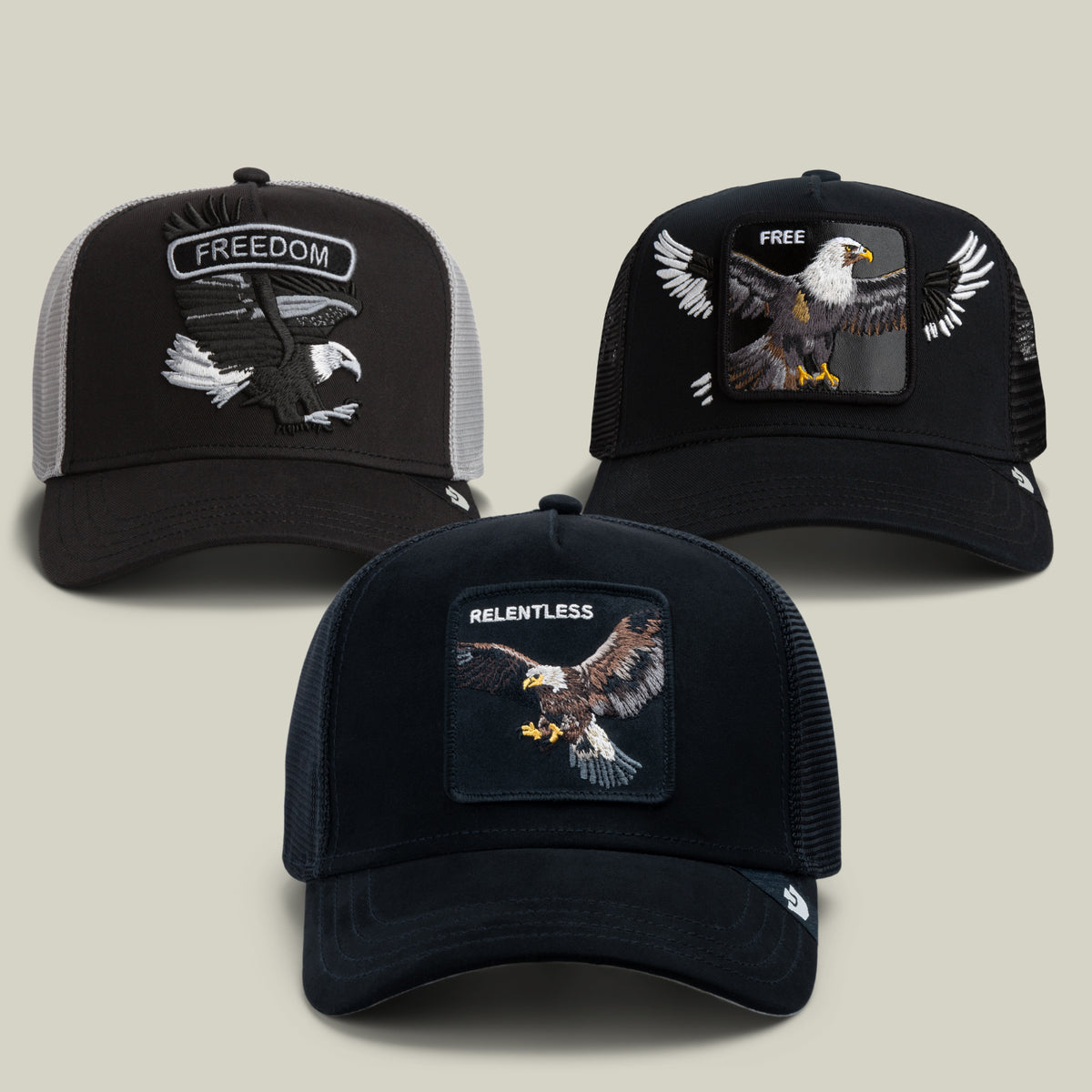 The Take Flight Bundle by Goorin Bros. includes three eagle caps featuring dramatic birds of prey graphics and bold lettering: FREEDOM on black and gray, FREE on black, and RELENTLESS on dark blue; each hat comes with a mesh back and a curved brim.