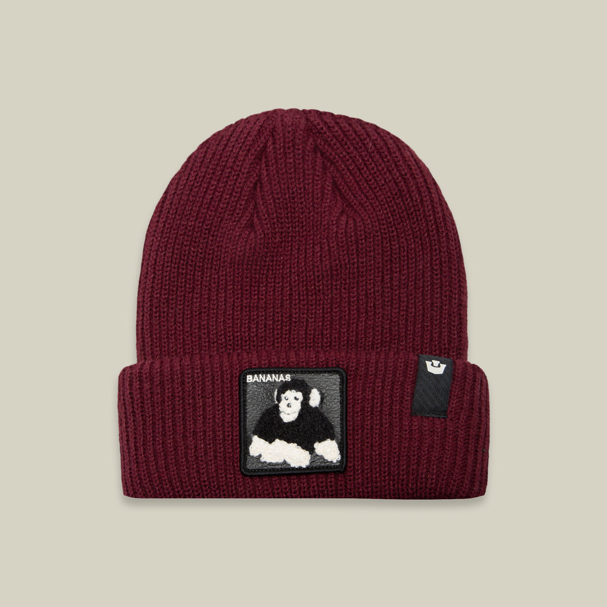 Stay warm and stylish with the Goorin Bros. Double Stuffed - Bananas Beanie, a maroon rib knit winter hat featuring a rectangular black patch on the front cuff with a playful white and black cartoon gorilla and the text “BANANAS.”.