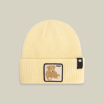 The Double Stuffed - Teddy Beanie by Goorin Bros. is a yellow knit hat with a folded, rib-knit cuff, featuring a teddy bear patch and a small black tag on the front—your cozy go-to winter accessory.