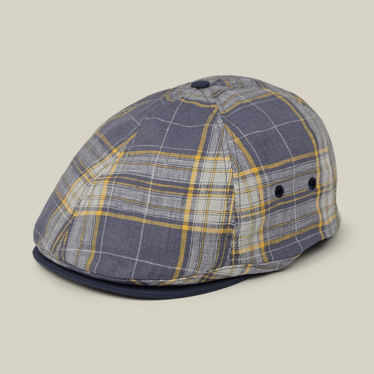 The Point Lobos 6 Panel Ivy flat cap by Goorin Bros., handmade in the USA from a breathable gray and yellow plaid cotton blend, features a button on top and two side ventilation eyelets, and is displayed on a neutral background.