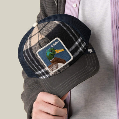 A person holding the Goorin Bros. Brit Cheeky cap, a plaid mesh hat featuring a front patch with an embroidered mallard duck and the word “CHEEKY.”.