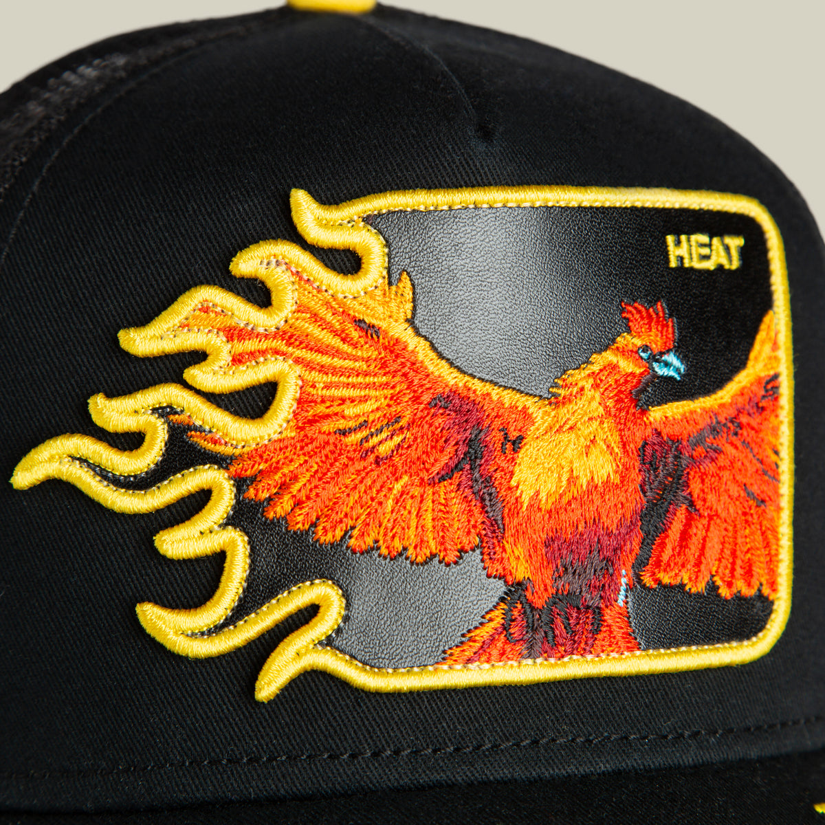 Black cap by Goorin Bros. featuring an embroidered fiery phoenix with outstretched wings, accented by a yellow border and the word “HEAT” stitched in the top right corner—Heat Flames is a bold statement hat for those with standout style.