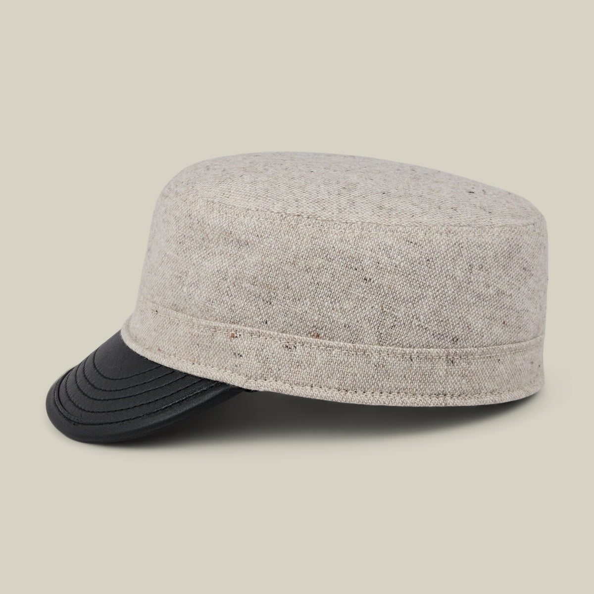The Goorin Bros. South Boulder cap, a heritage-inspired beige tweed style with a black curved visor, is displayed against a plain light background. Expertly hand cut and sewn in the USA from quality wool and leather, this cadet cap showcases exceptional craftsmanship and timeless design.