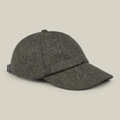 Valmont by Goorin Bros. is an olive green wool baseball cap featuring a curved brim, metal eyelets for ventilation, and an adjustable strap at the back. Proudly made in the USA, it is showcased on a plain beige background.