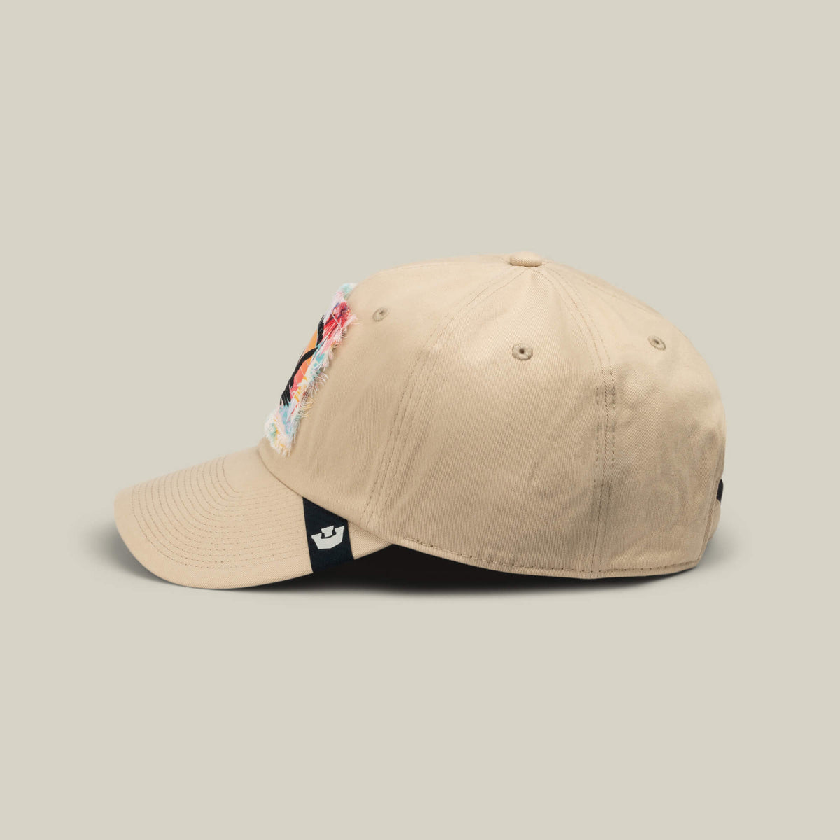 Beige baseball cap from Goorin Bros., called GTFO, featuring a vibrant S.O.S. Island patch on the front and a black side tag with a white logo, pictured against a simple light background—a look that brings to mind something Colonel Banu McGuven would sport in the mess hall.