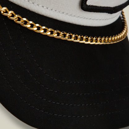 Close-up of a Goorin Bros. Mini CapLoc Chain—a bold double clip chain in gold, styled as hat jewelry on a black and white baseball cap, running along the front above the brim.