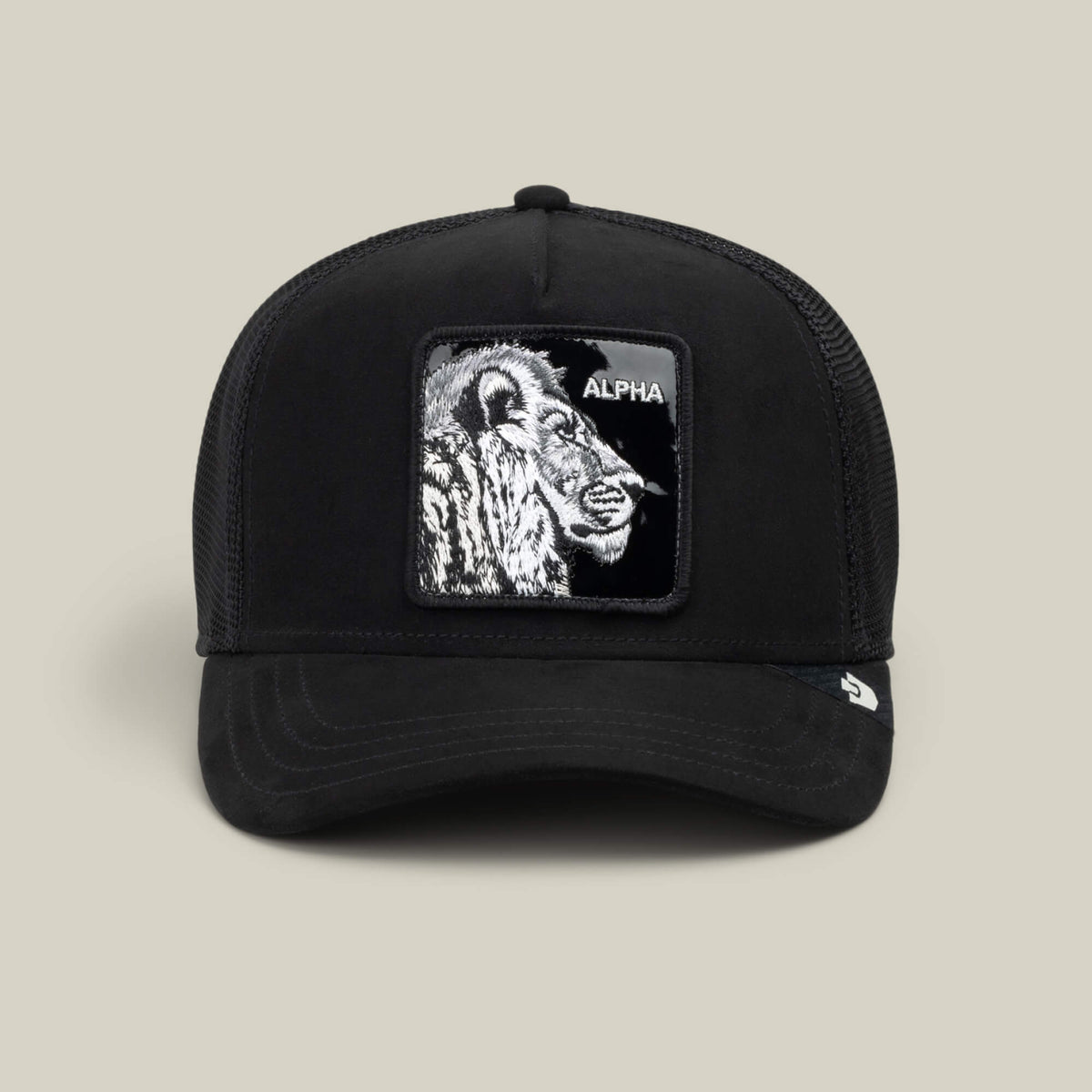 The Goorin Bros. Black Out Lion trucker hat features a bold embroidered lion patch with the word “ALPHA” on the front and is displayed against a neutral background.