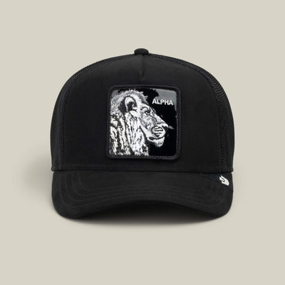 The Goorin Bros. Black Out Lion trucker hat features a bold embroidered lion patch with the word “ALPHA” on the front and is displayed against a neutral background.