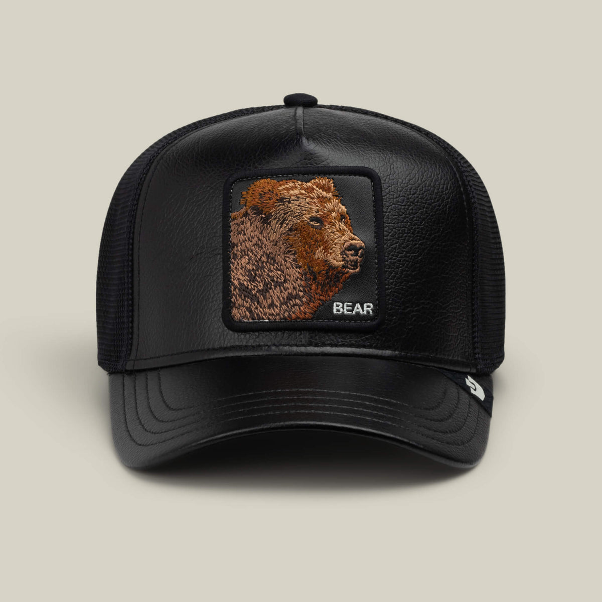 The Goorin Bros. Faux Leather Bear is a black faux leather trucker hat featuring breathable mesh sides and a stitched, embroidered grizzly bear patch with the word “BEAR” on the front.