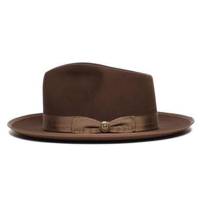Introducing the River Gray by Goorin Bros.—a wide brim fedora in a sophisticated brown hue, styled with an indented crown and expertly crafted from soft merino wool. Accented with a brown ribbon band and a delicate side button, this American-made accessory blends timeless design with premium materials for a truly distinguished look.