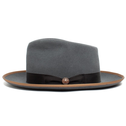 River Gray by Goorin Bros. is an elegant American-made merino wool fedora, featuring a wide brown-trimmed brim, black ribbon band, and a small round metal pin on the front—perfect for any occasion.