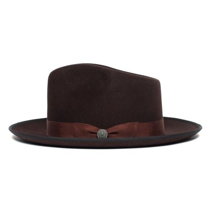 A dark brown merino wool fedora called “River Gray” by Goorin Bros., featuring a matching ribbon band and a small metal emblem, displayed against a plain white background.