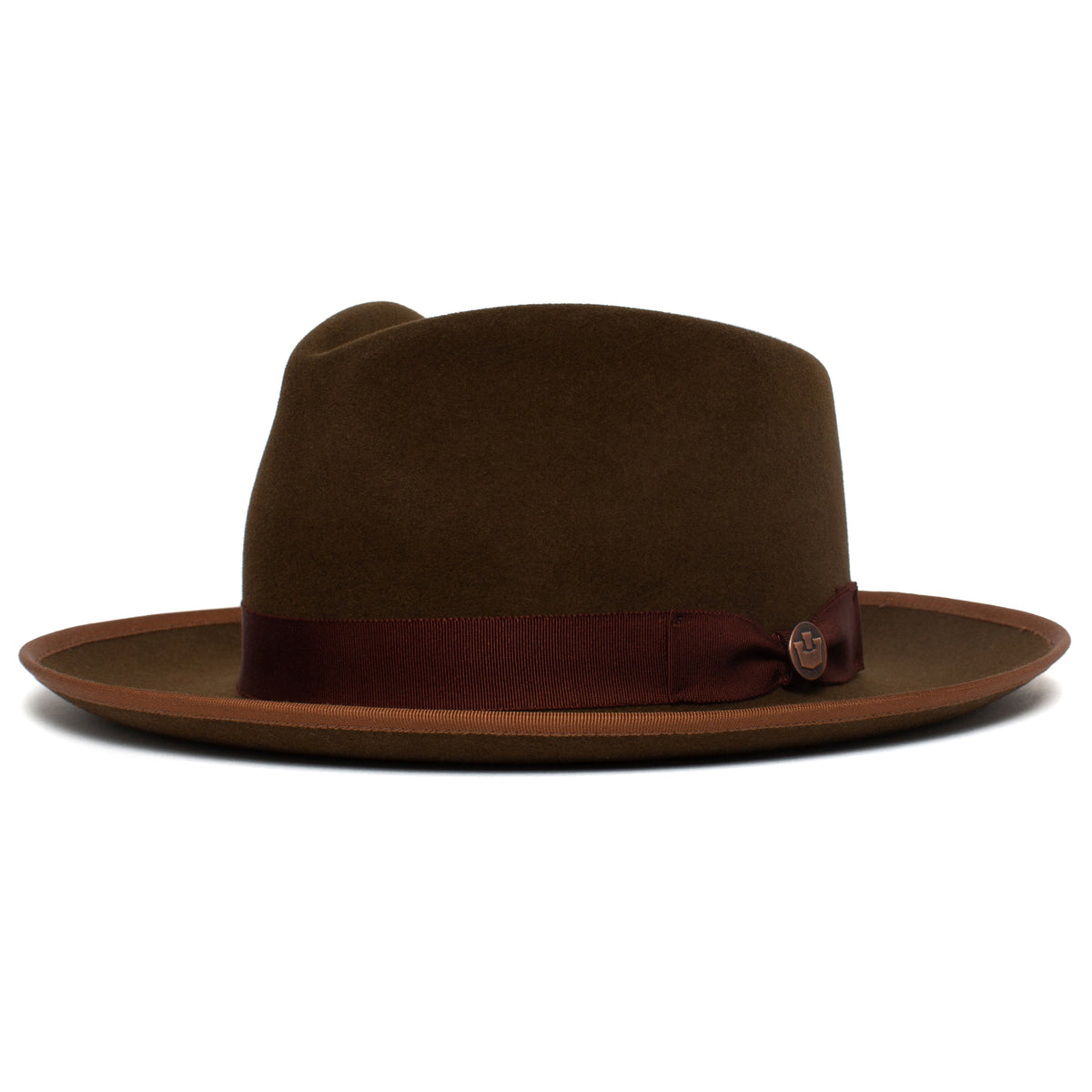 Introducing the River Gray by Goorin Bros.—a wide brim fedora featuring a rich brown felt, adorned with a matching trim and a dark red ribbon band accented by a small decorative emblem on the side. Expertly crafted in the USA from premium merino wool, this hat showcases timeless style and refined sophistication through its quality materials and expert construction.