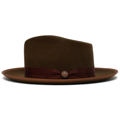 The River Gray by Goorin Bros. is a wide brim felt fedora in brown, featuring a burgundy ribbon band with a small round badge accent. Expertly crafted in the USA from quality merino wool, this hat showcases a refined finish with slightly lighter trim along the brim edge.